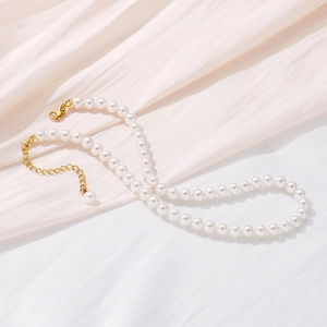 Detail of white pearl necklace with golden lobster clasp on elegant pink silk background