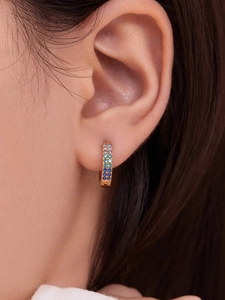 Detail shot of golden huggie earrings with gradient blue and purple crystals on ear