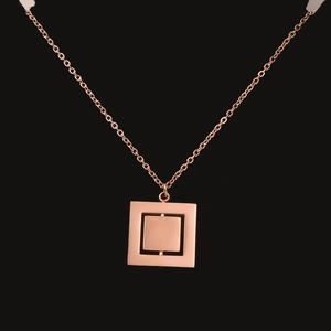 Macro detail of rotating rose gold square pendant necklace on a black background