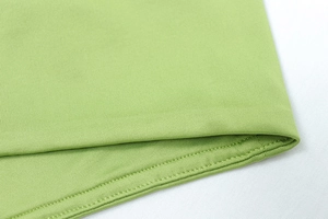 Close-up of light green sportswear fabric showing high-quality double-stitch hem details