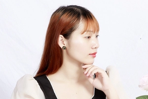 Close-up of elegant black and gold Eye of Horus stud earring worn on a model's ear