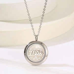 Macro shot of silver round necklace pendant with white pearls and Mae engraving text