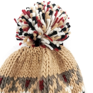 Detail shot of winter knit beanie showing texture, pom-pom and jacquard patterns