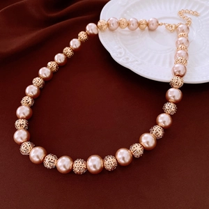 Detailed shot of pearl necklace with golden hollow beads and lobster clasp on velvet