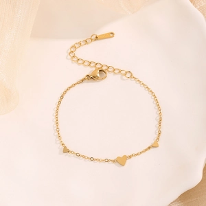 Elegant gold titanium steel heart pendant bracelet on a ceramic tray with soft tulle