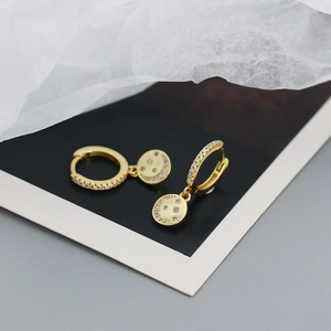 Macro detail of gold-plated hoop earrings with crescent moon and star zircon charms
