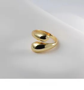 Macro detail of high-polish 18K gold teardrop ring with mirror finish on white fabric