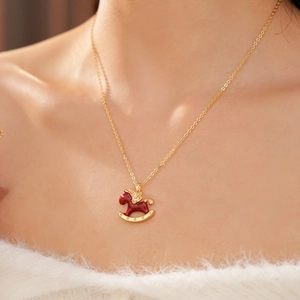 Detail shot of the golden horse pendant with red enamel on a model's neck for a warm look