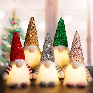 Five glowing Christmas gnomes with colorful sequin hats on a festive background