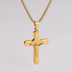 Détail macro du collier croix en acier doré avec gravure de Jésus et Saint-Benoît