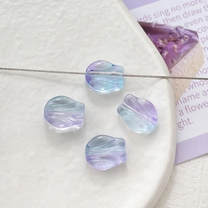 Macro detail of gradient purple and blue tulip-shaped glass beads on ceramic plate