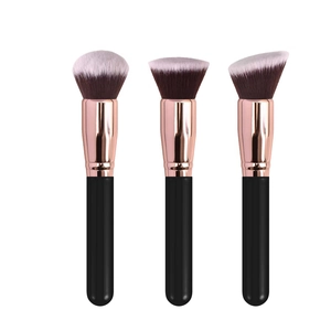 Three professional makeup brushes with rose gold ferrules and black handles on white background