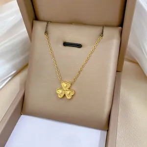 Detailed close-up of golden clover pendant with radial brushed texture in a jewelry box
