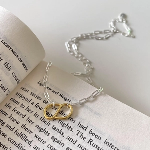 Detail of interlocking gold rings pendant on a silver necklace over an open book