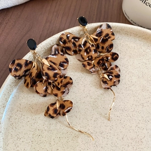 Detailed macro view of leopard print fabric flower earrings with gold tassel accents