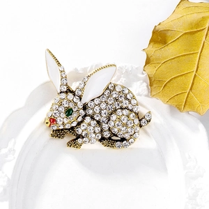 Detail of crystal rabbit brooch with white rhinestones and green gem eyes on a white frame