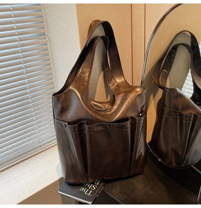 Detailed view of dark brown multi-pocket tote bag with polished faux leather finish