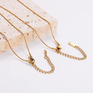 Elegant gold stainless steel snake chain necklaces set on minimalist stone display