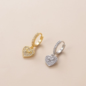 Macro shot of gold and silver heart-shaped zircon pendants on elegant hoop earrings