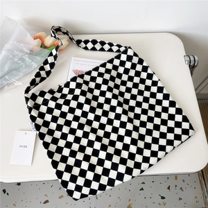 Flat lay view of a checkerboard canvas bag with miss tag on a white table background
