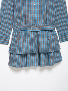 Détail d'une robe à carreaux bleu et marron avec ceinture et ourlet à volants superposés