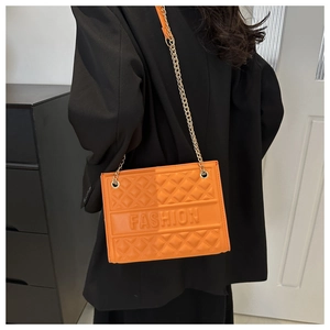 Detail view of orange embossed crossbody bag with fashion lettering and chain strap