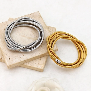 Detail of stacked multi-layer gold and silver spring coil bracelets on stone slab