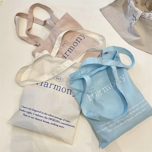 Detailed shot of canvas tote bags in pink, beige, and blue with minimalist lettering