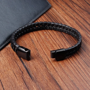 Detail of double-layer black braided leather bracelet with black magnetic clasp on wood