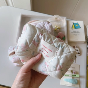 Détail d'une trousse à maquillage en coton matelassé avec fleurs et fermeture éclair