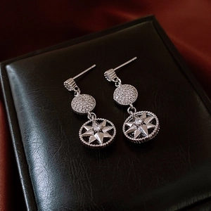 Détail de boucles d'oreilles étoile argentées avec cristaux sur étui en cuir noir