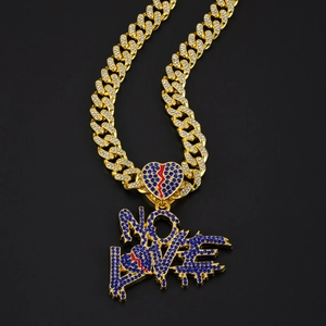 Close-up of gold Cuban chain with NO LOVE blue rhinestone pendant and red heart detail