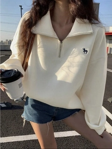 Λεπτομέρεια κεντήματος μονόκερου στο κρεμ oversized φούτερ με φερμουάρ για γυναίκες