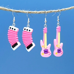 Pink musical instrument earrings featuring an accordion and electric guitar on a blue backdrop