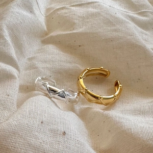 Detailed view of gold and silver textured rings on soft beige linen fabric background