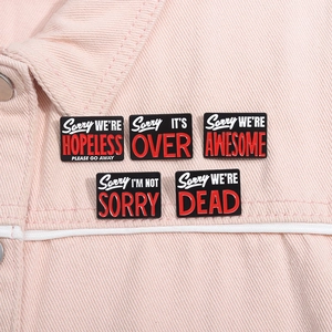Detail of five enamel square badges with funny phrases on a pink denim jacket