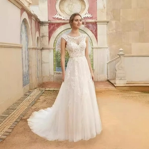 Elegant white lace A-line bridal gown with illusion neckline and tulle skirt in outdoor setting