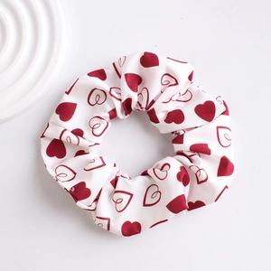 Top view of a white fabric scrunchie featuring a red heart pattern on a clean background