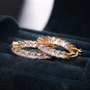 Detailed view of gold plated hoop earrings with square cubic zirconia in a velvet box