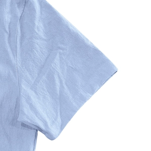 Close-up of the light blue linen shirt sleeve seams and high-quality fabric texture