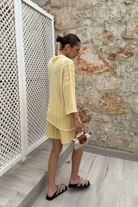 Détail de la maille ajourée jaune clair sur l'ensemble polo et short décontracté