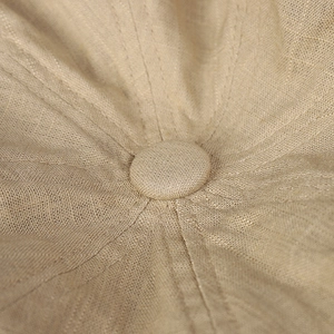 Détail macro de la texture en lin et du bouton central renforcé du chapeau pare-soleil