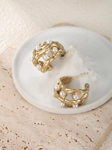 Detail of vintage gold C-shape hoop earrings with irregular texture and white pearls