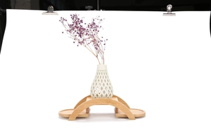 Close-up of a white cutout ceramic vase on a bamboo arch bridge display stand