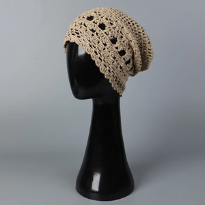 Primer plano de gorro de ganchillo beige con patrón floral calado sobre maniquí