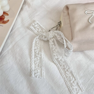 Detail of cream canvas makeup bag with lace bow and embroidered floral patterns