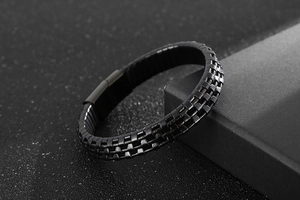 Detail shot of the black woven leather texture and matte magnetic clasp on men's bracelet