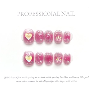 Detail of pink press-on nails featuring glitter, 3D hearts, pearls, and bear charms