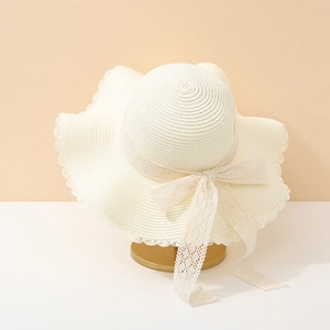 Detail of cream straw sun hat featuring scalloped edges and elegant lace bow decoration