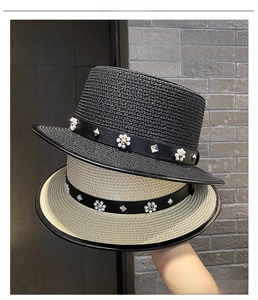 Detail of straw sun hat with leather band, pearl flower and metal rivets decoration